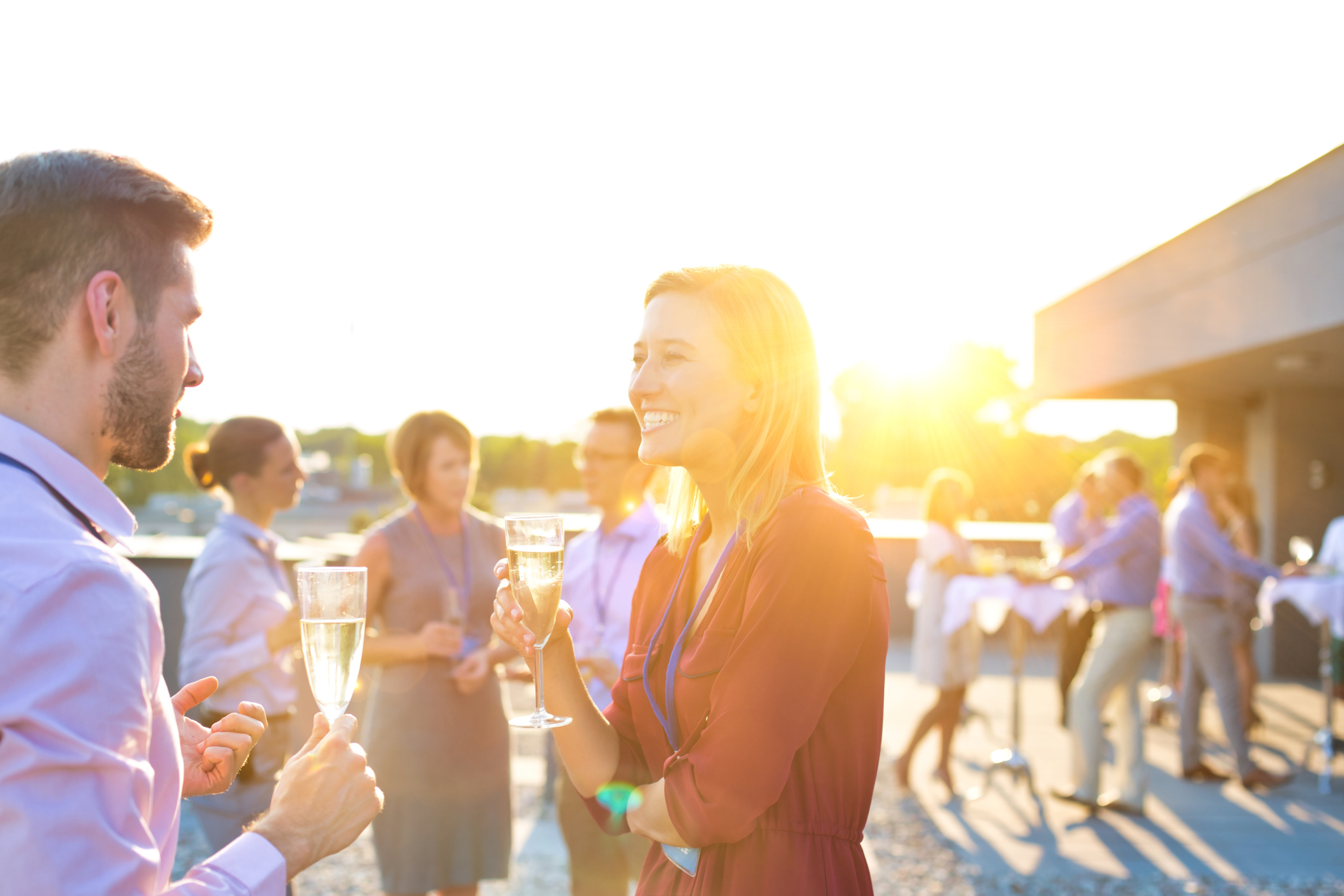 Smiling businesswoman drinking champagne while talking to colleague in rooftop success party
