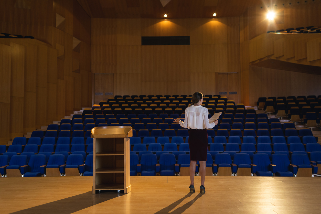 Rear view of businesswoman practicing and learning speech while standing in the auditorium