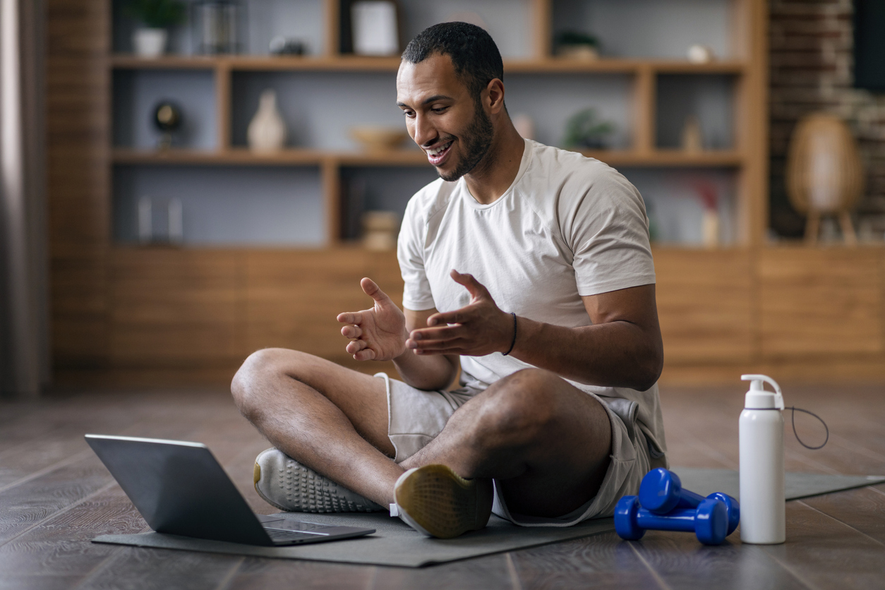 Remote Wellness Trainings. Young man tuning into virtual yoga